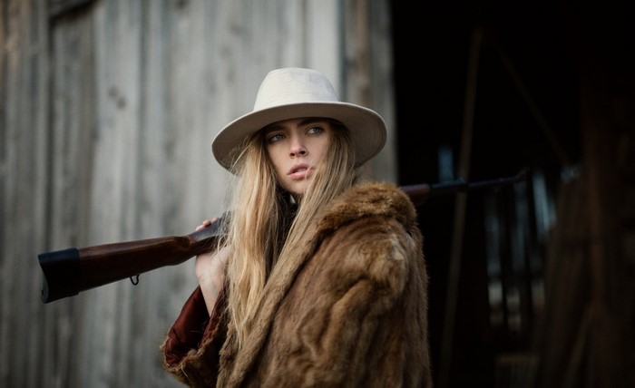 Woman in fur coat and hat holding a rifle
