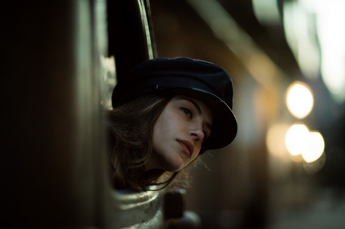 Woman wearing a black hat looking out a window