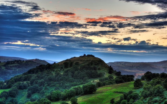 Castle ruins on a grassy hill at sunset
