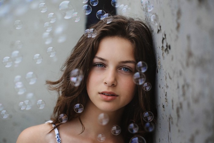 Young woman with blue eyes and brown hair surrounded by bubbles