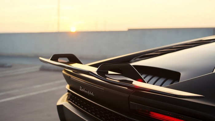 Black Lamborghini Huracan with rear spoiler at sunset