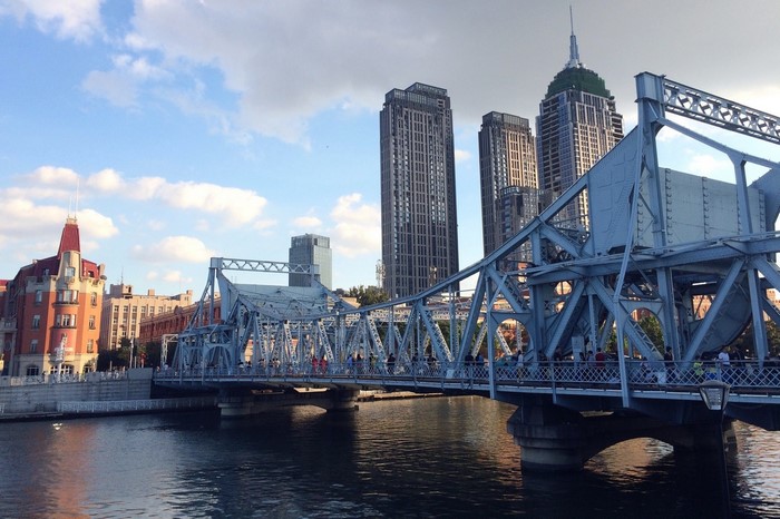 Steel bridge over a river in Tianjin, China with skyscrapers