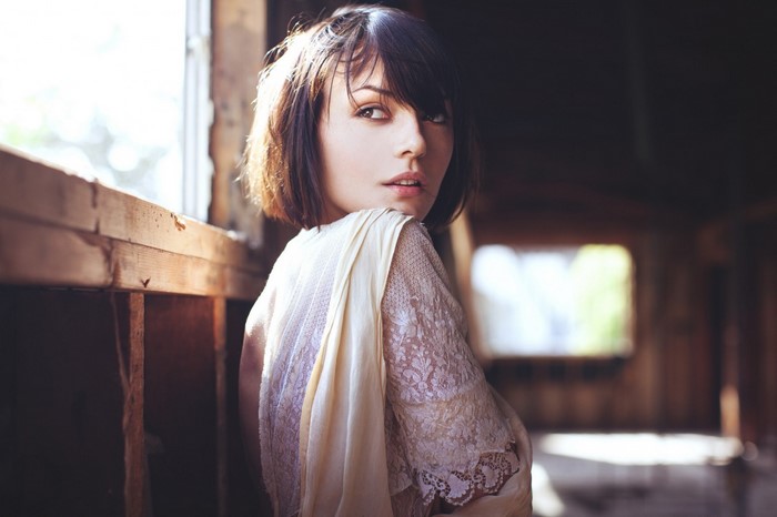Woman in lace dress looking over shoulder by window