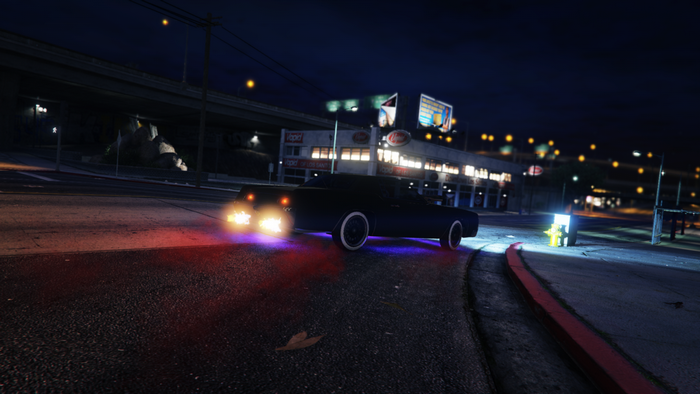 Dark sedan with glowing taillights on a city street at night