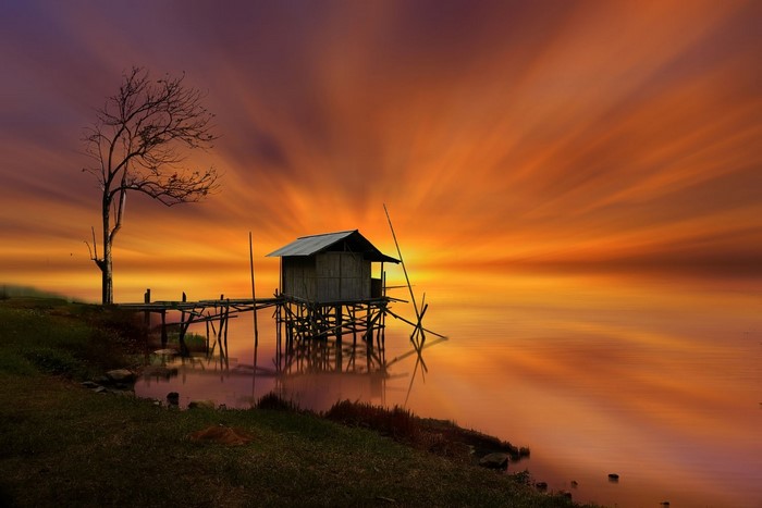 Hut on stilts by a lake at sunset