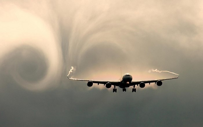 Airplane creating vortex in clouds