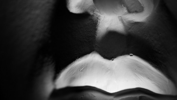 Monochrome close-up of a sculpture's face with dramatic lighting