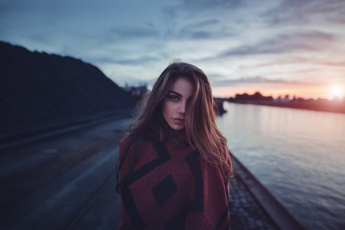Woman in poncho by river at dusk