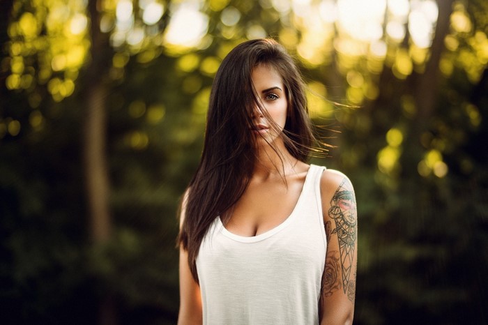 Woman with tattoo in white tank top outdoors