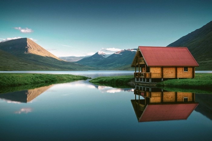 Log cabin on a lake with mountains and reflection