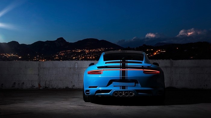 Blue Porsche 911 Carrera S at night with city lights