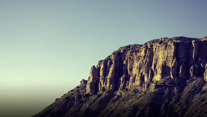 Sunlit cliff face against a clear sky