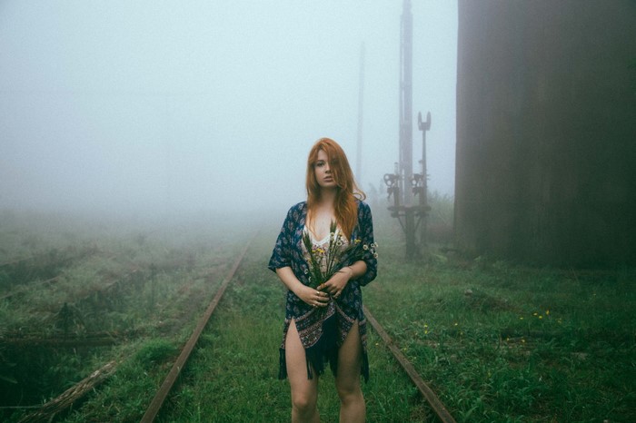 Redhead Woman Standing on Misty Railway Tracks