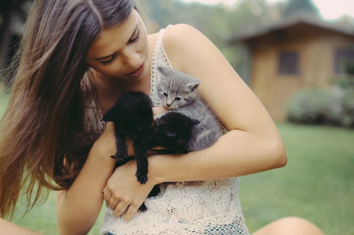 Woman holding three kittens outdoors