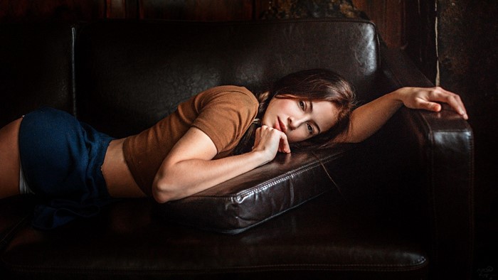 Woman lying on a dark leather couch