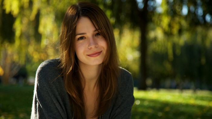 Woman smiling outdoors in sunlight