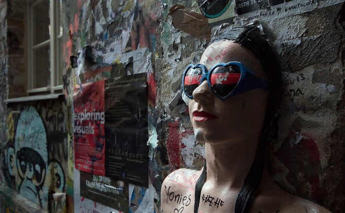 Mannequin with heart-shaped glasses on a graffiti-covered wall