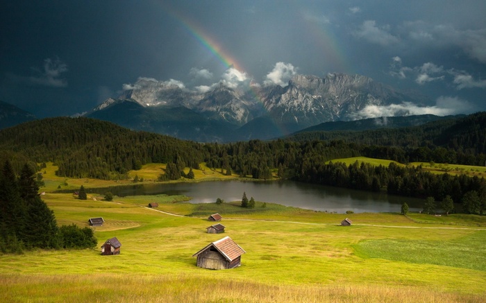 Double rainbow over mountains and lake with cabins