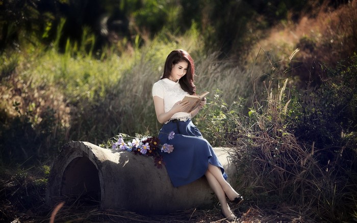 Woman reading a book outdoors with flowers