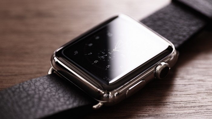 Apple Watch with black leather band on wooden surface
