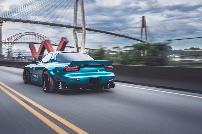 Blue Mazda RX-7 Rocket Bunny driving on a bridge