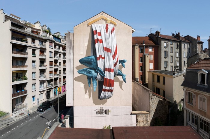 Mural of whales and striped fabric on a building facade in Grenoble