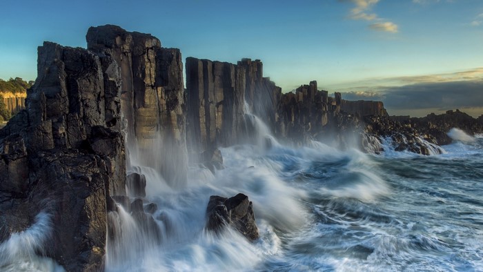 Waves crashing against dark rock formations on the coast