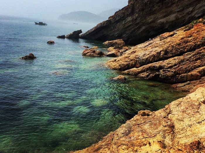 Rocky coast with clear turquoise water and boats