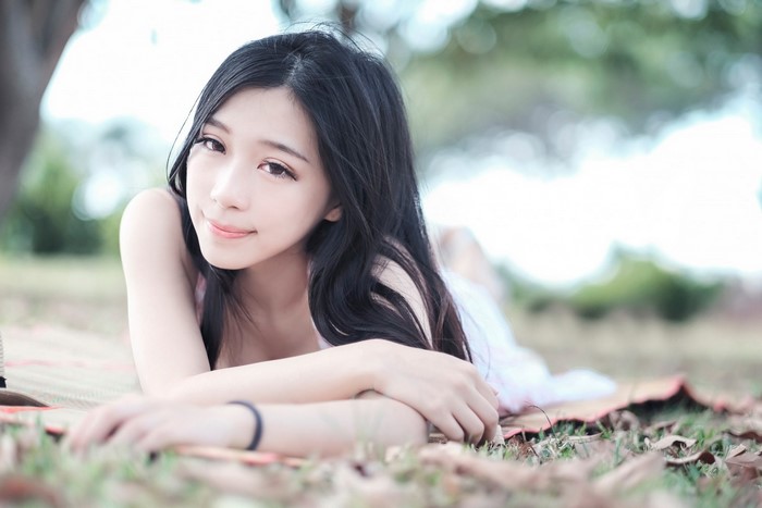 Asian woman with long black hair lying on grass