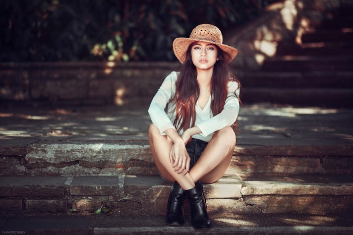 Woman wearing a straw hat and white shirt sitting on stairs