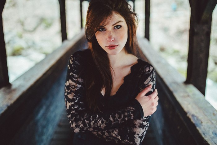 Woman with long brown hair wearing a black lace dress