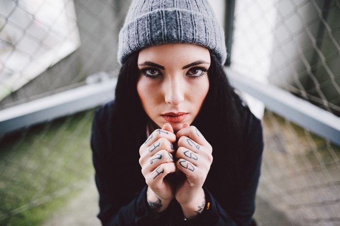 Woman with tattoos wearing a beanie looking at viewer
