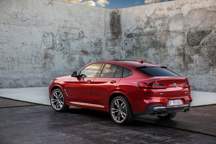 Red BMW X4 parked near a textured wall