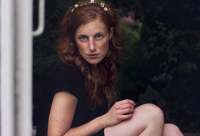 Woman with freckles and flower crown looking at viewer