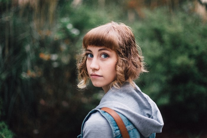 Woman with short wavy hair looking over shoulder