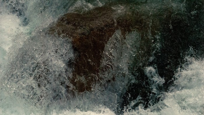 Water crashing over a dark rock