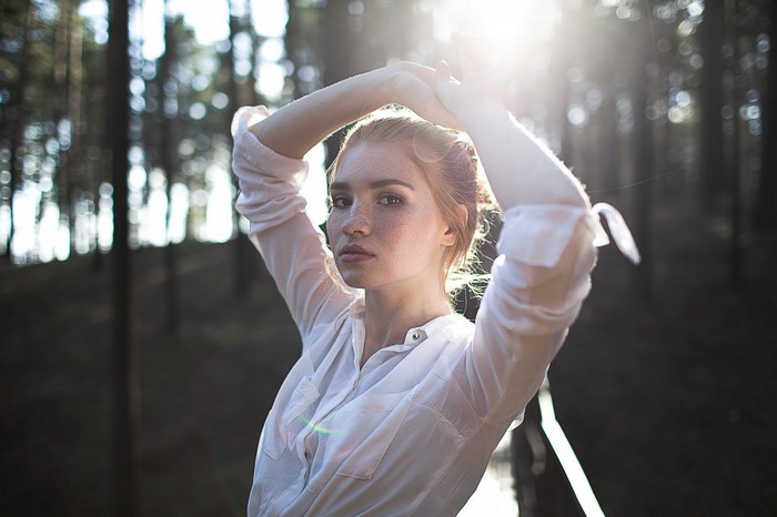 Woman with freckles in a white shirt outdoors