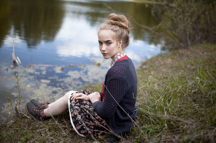 Young woman sitting by a lake in nature