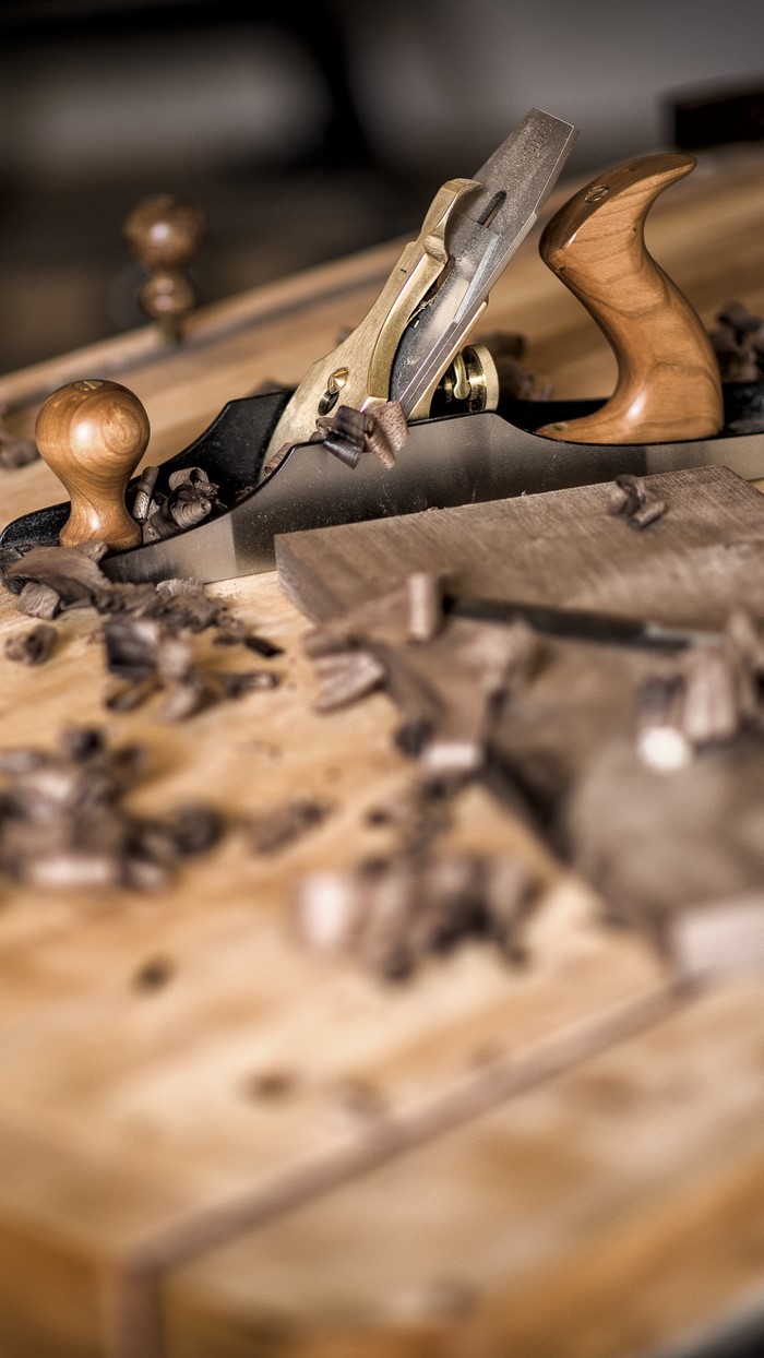 Woodworking plane with shavings on a wooden surface
