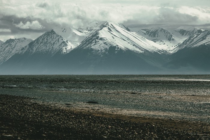 Snow-capped mountains over a rocky shore