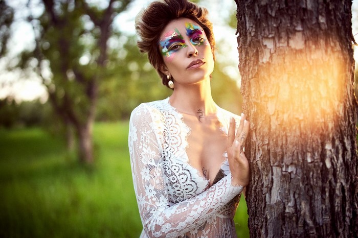 Woman with colorful face paint in a white lace dress