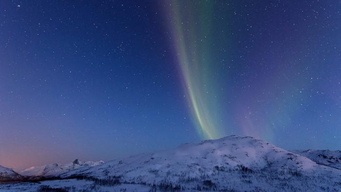 Aurora Borealis over snow-covered mountains at night
