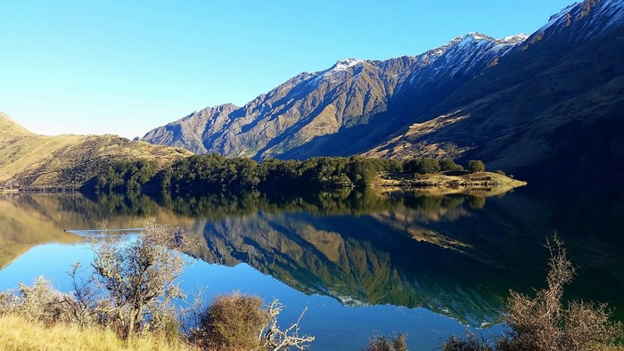 Lake reflection of snow-capped mountains and trees