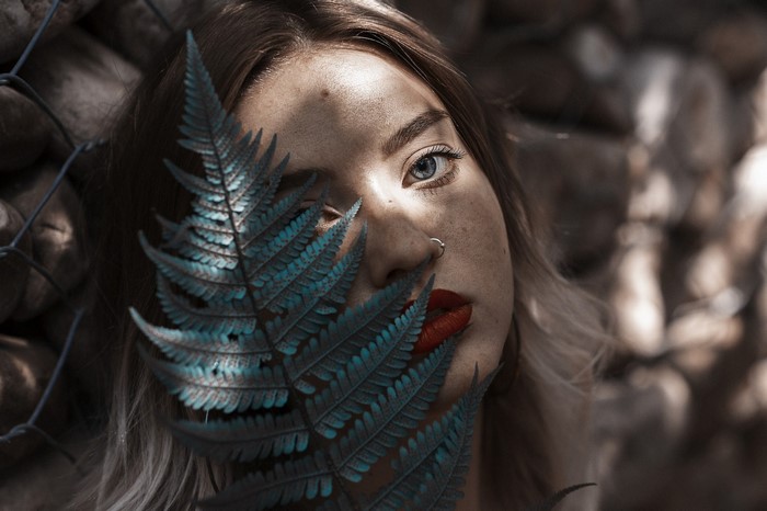 Woman with fern leaf covering face