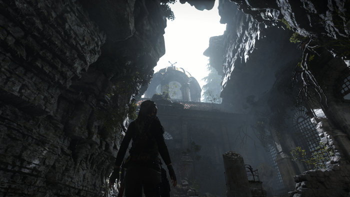 Lara Croft in a cave looking at ancient ruins