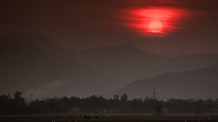 Red sun setting behind misty mountains