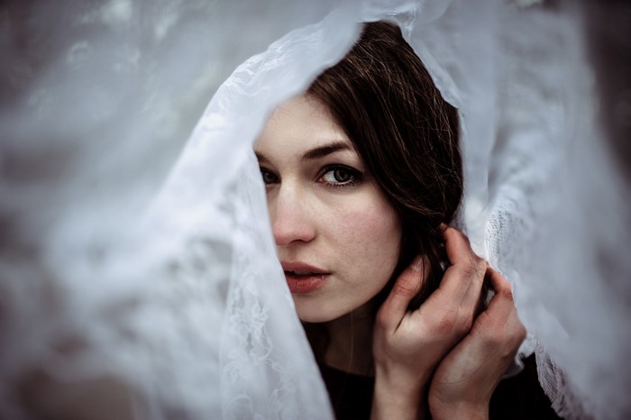 Woman peeking through a white veil