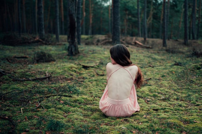 Woman in pink dress sitting in a forest