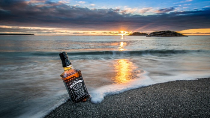 Jack Daniels bottle on a beach at sunset