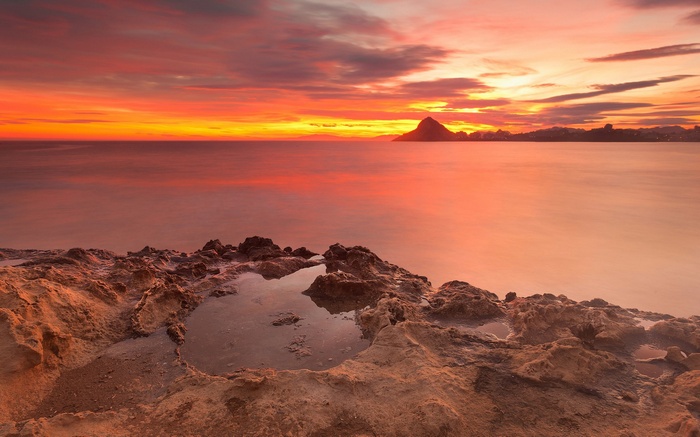 Sunset over the ocean with rocky foreground